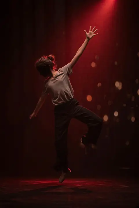 Dancer with an open hand reaching into the spotlight